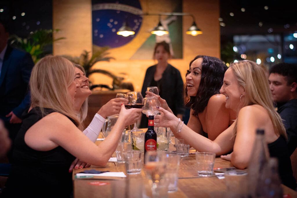 A group of women joyfully toasting with glasses at York restaurant Casa Brazilian Rodizio, they are celebrating a special occasion together.