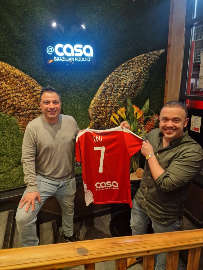 Owner of Casa Rodizio Eduardo stood with York Futsal Vikings holding up a red t-shirt.