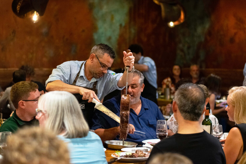 Casa Brazilian Rodizio waiter carving grilled beef at the table for guests in York.