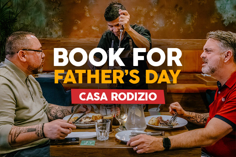 Two fathers enjoying a Brazilian rodizio dining experience at Casa Rodizio York as fresh grilled meat is carved at the table for a Father's Day celebration.