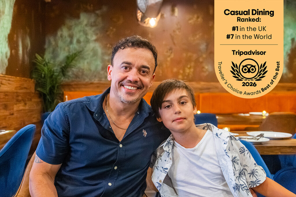 Casa Brazilian Rodizio owner Eduardo and his son seated together in the restaurant, with a Tripadvisor awards graphic in the top right.